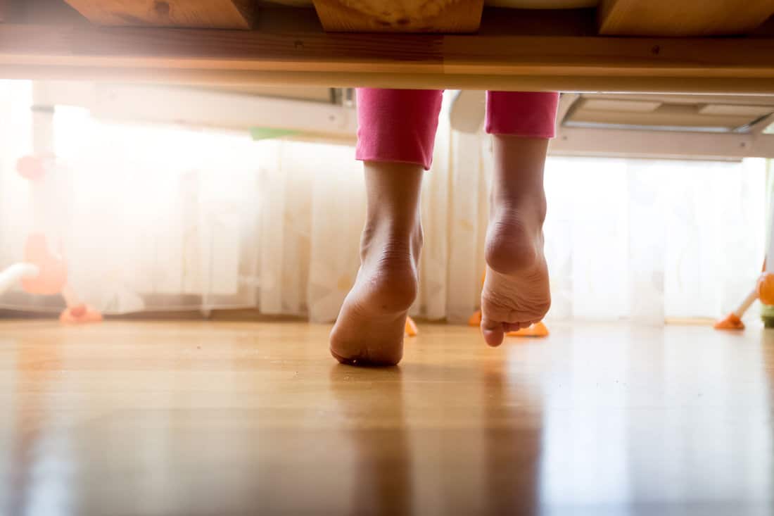 Image from under the bed on girl stepping on floor
