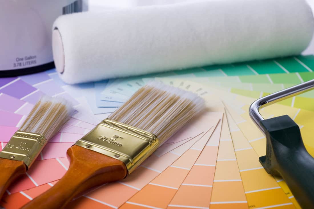 Image of paint brushes, roller, paint can, and paint samples