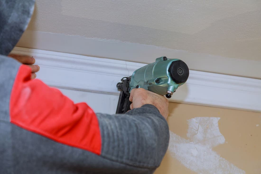 Installation of crown moldings trim on the ceiling of the using gauge finish nailer