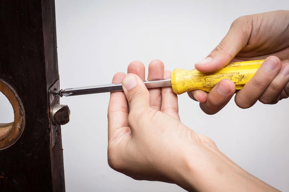 Locksmith use old screwdriver fix the lock on old wooden door