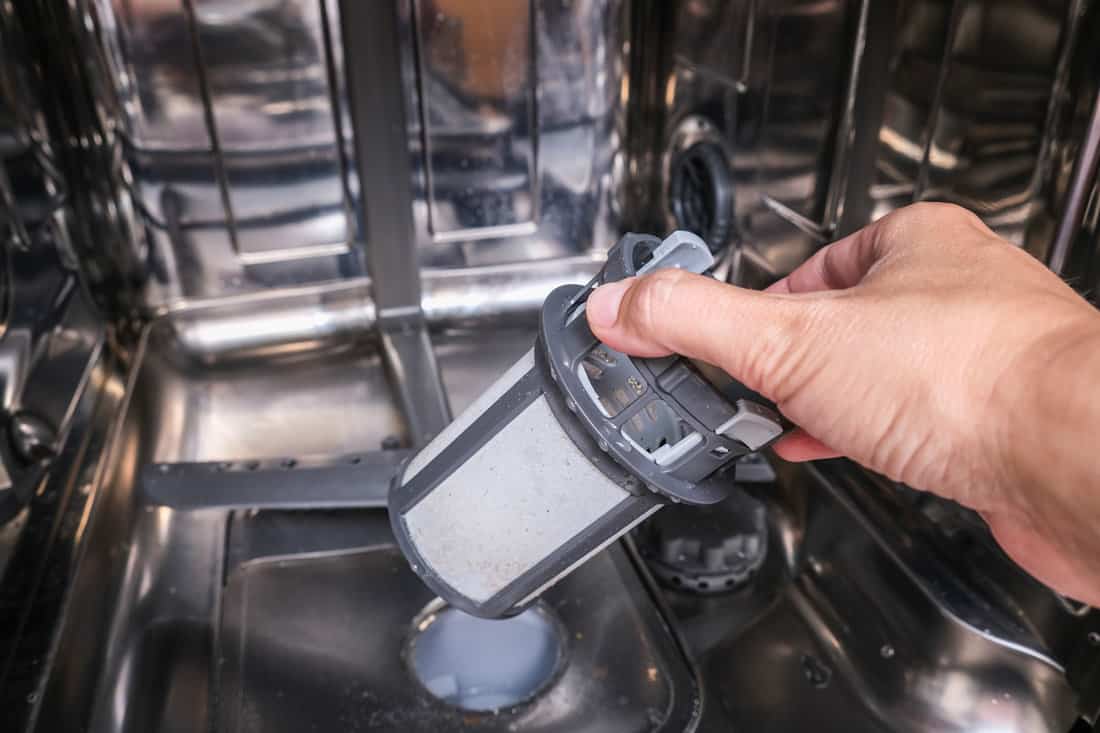 Man removing dishwasher filter for cleaning