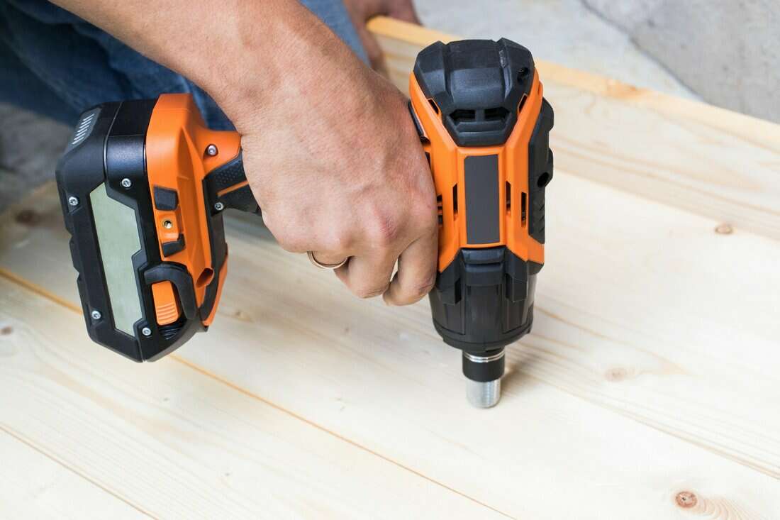 Men Hand Drilling Wooden Board With Battery Driller / Impact Wrench For Residential Construction Work Close Up.