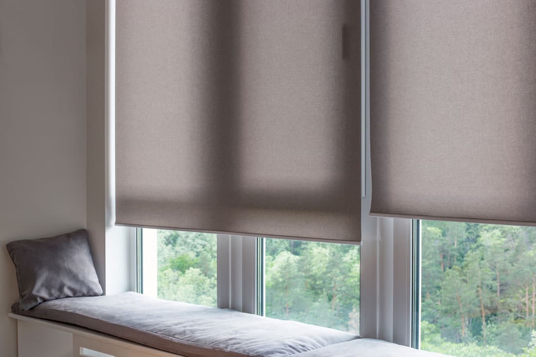 Motorized roller shades. Automatic roller blinds beige color on large windows.