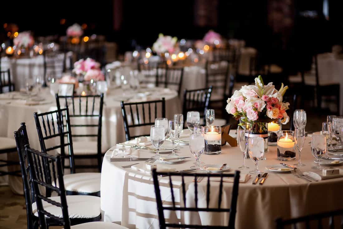 Multiple tables with centerpieces at an indoor elegant wedding reception 