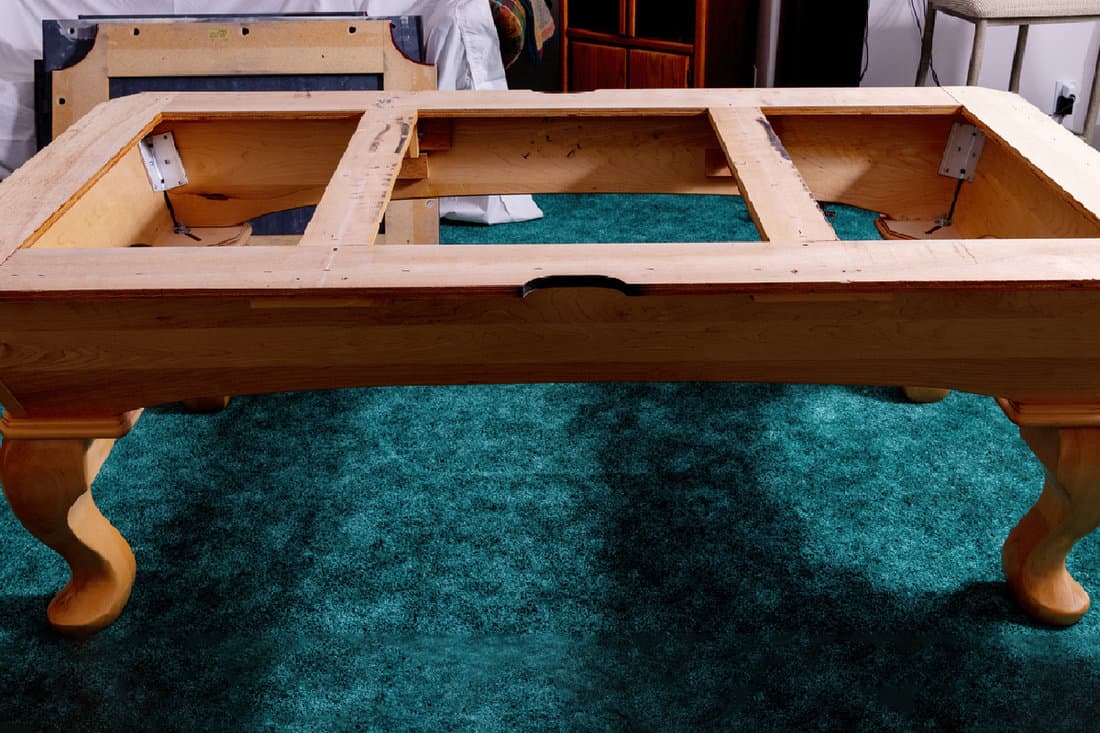 Oak wood pool table stand on green colored carpet