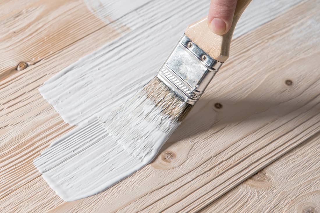 Painted wooden surface with brush and white paint.