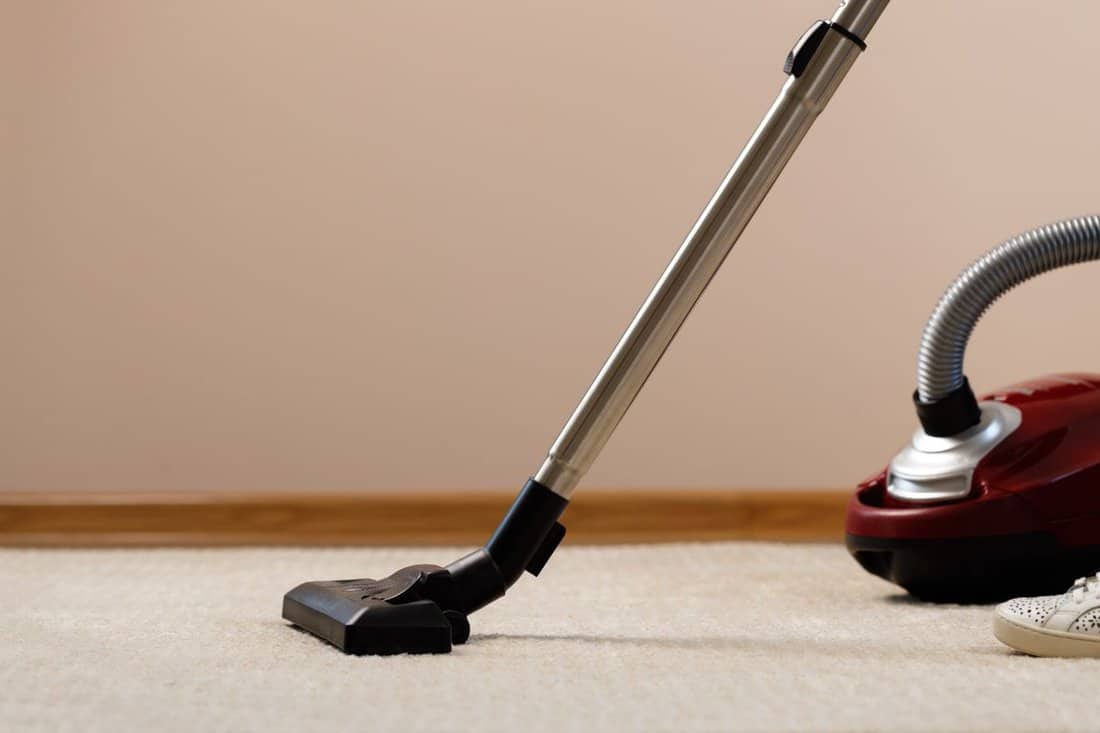 Red vacuum cleaner on a beige carpet.