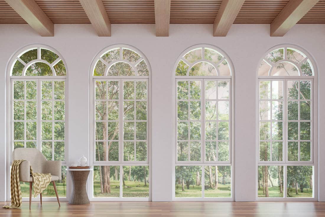 Scandinavian living room 3d rendering image.The Rooms have wooden floors and ceilings with white walls .There are arch shape window overlooking to the nature. 