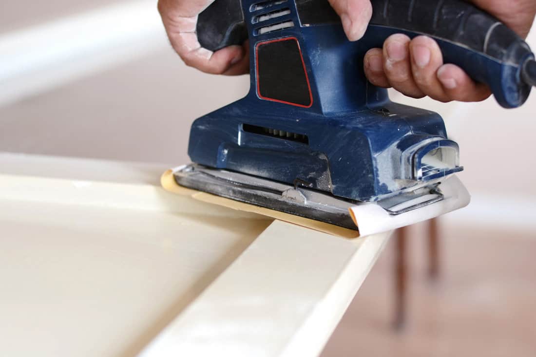 Sanding and preparing old doors with cracked paint for a new lick of paint, Smooth sanding or paint removal concept.