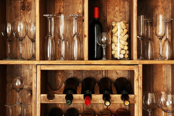 Shelving with wine bottles with glasses on wooden wall, Bormioli Rocco Vs Luigi Bormioli Glass: Differences Discussed