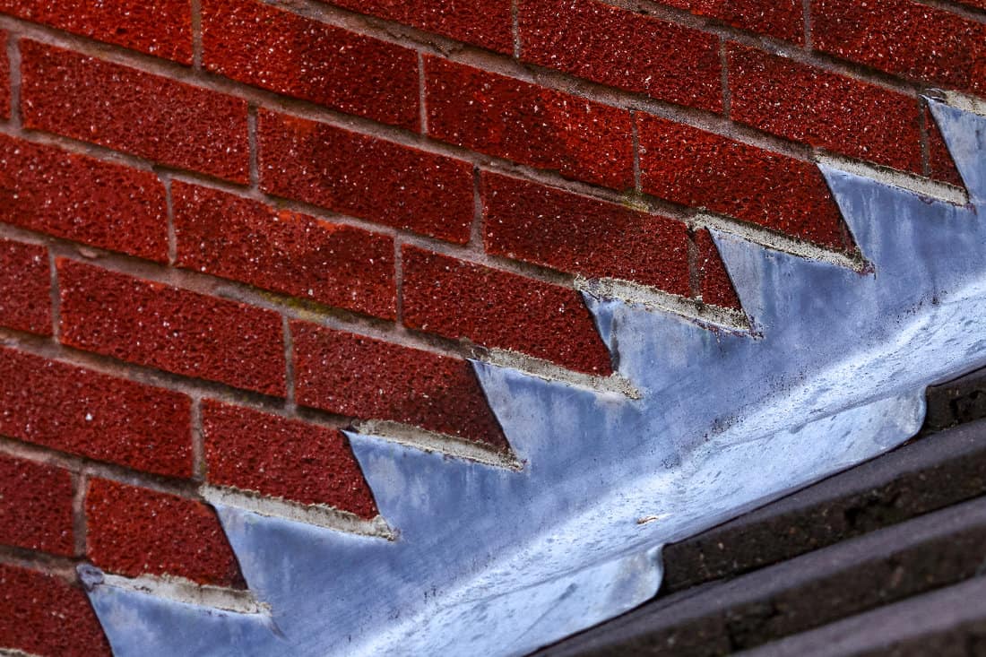 Stepped lead flashing roof gulley creating a water tight seal between roof tiles and brick wall