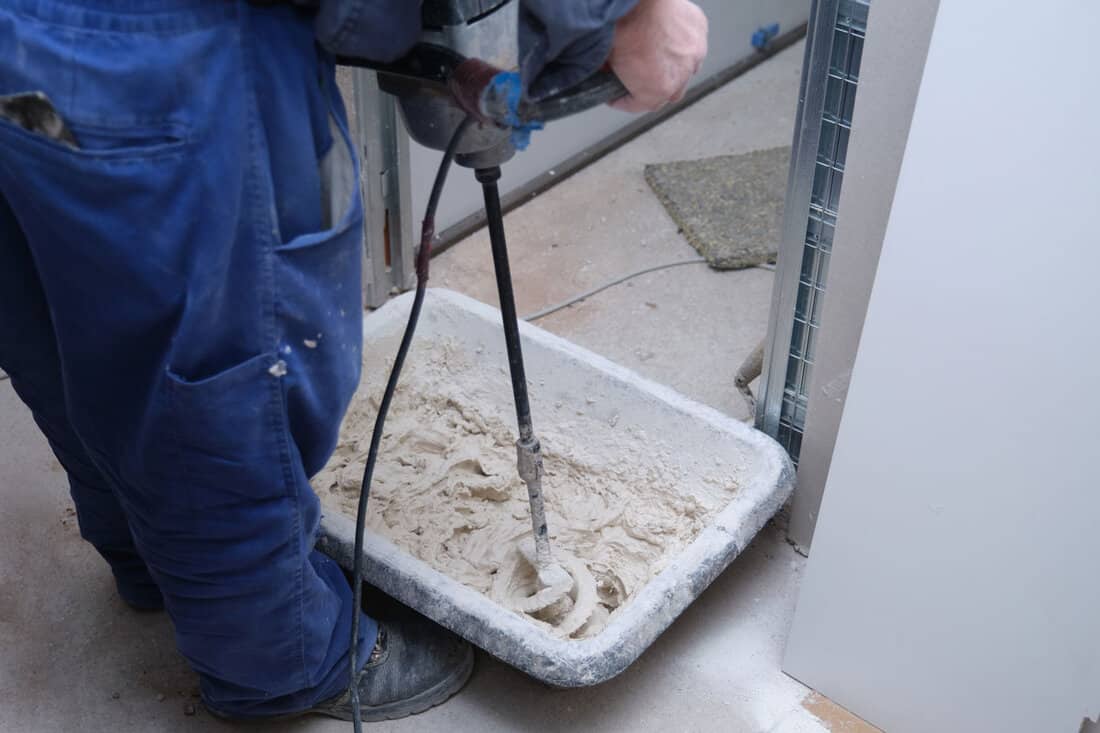 Unrecognizable worker preparing tile adhesive mortar with a hand mixer