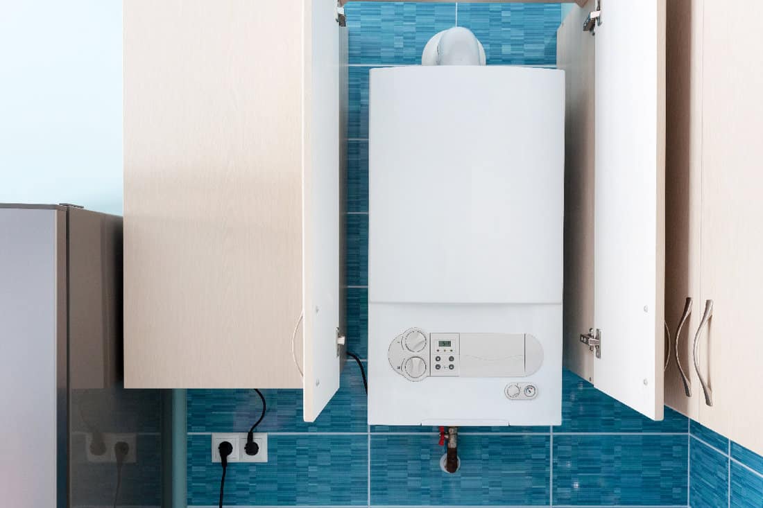 White gas boiler mounted in wall cupboard