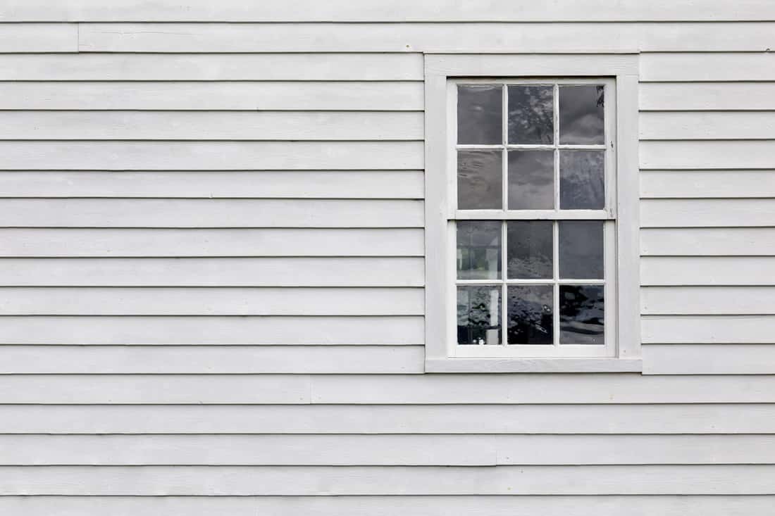 White wooden siding and a white framed window
