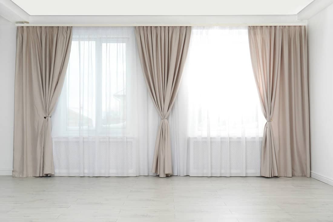 Windows with elegant curtains in empty room 