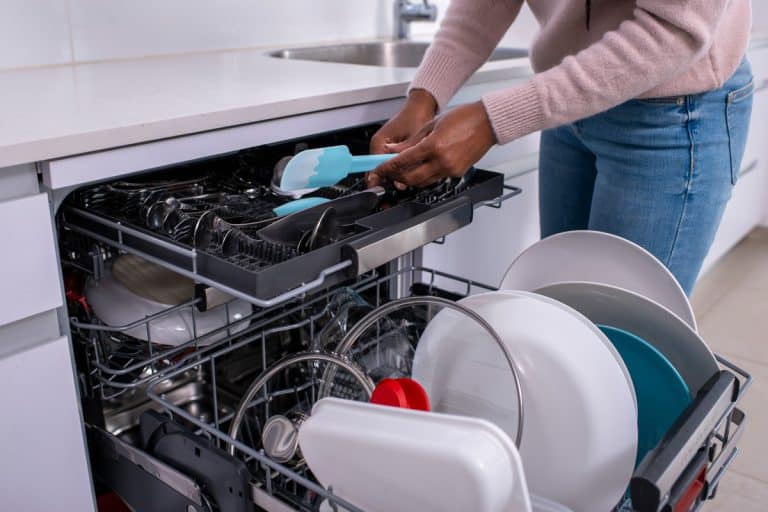 Woman putting used kitchen utensil inside the dishwasher, How To Get Rid Of Pink Mold In A Dishwasher