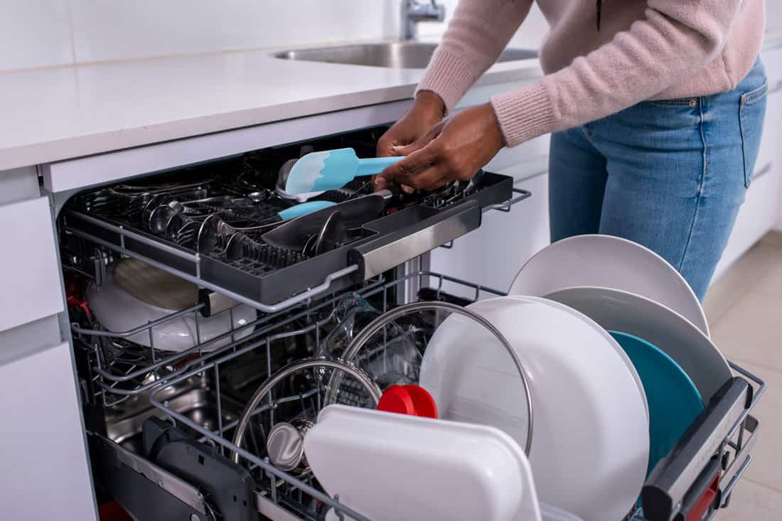 Woman putting used kitchen utensil inside the dishwasher