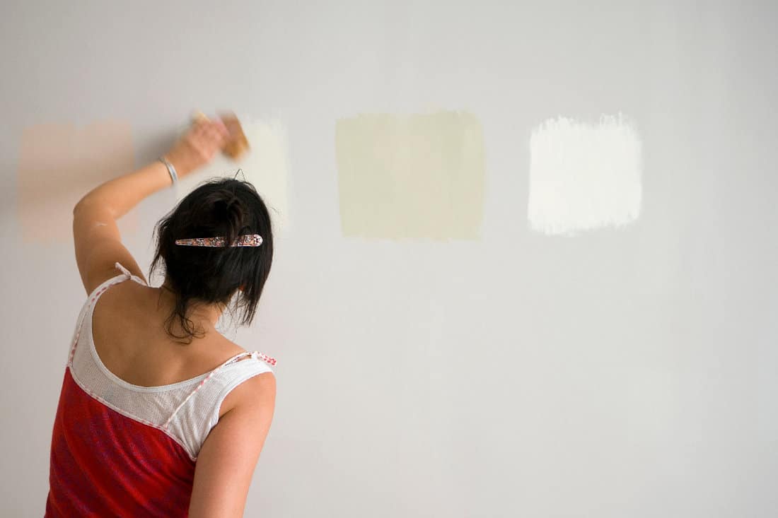 Woman testing different paint shades over the wall
