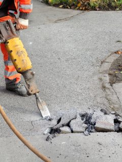 Worker at construction site demolishing asphalt with pneumatic plugger hammer, How To Cut Concrete Without A Saw