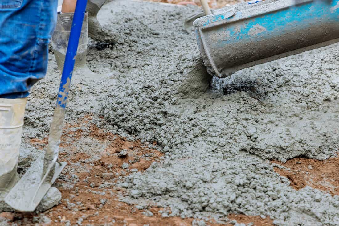 Worker evenly spreading concrete