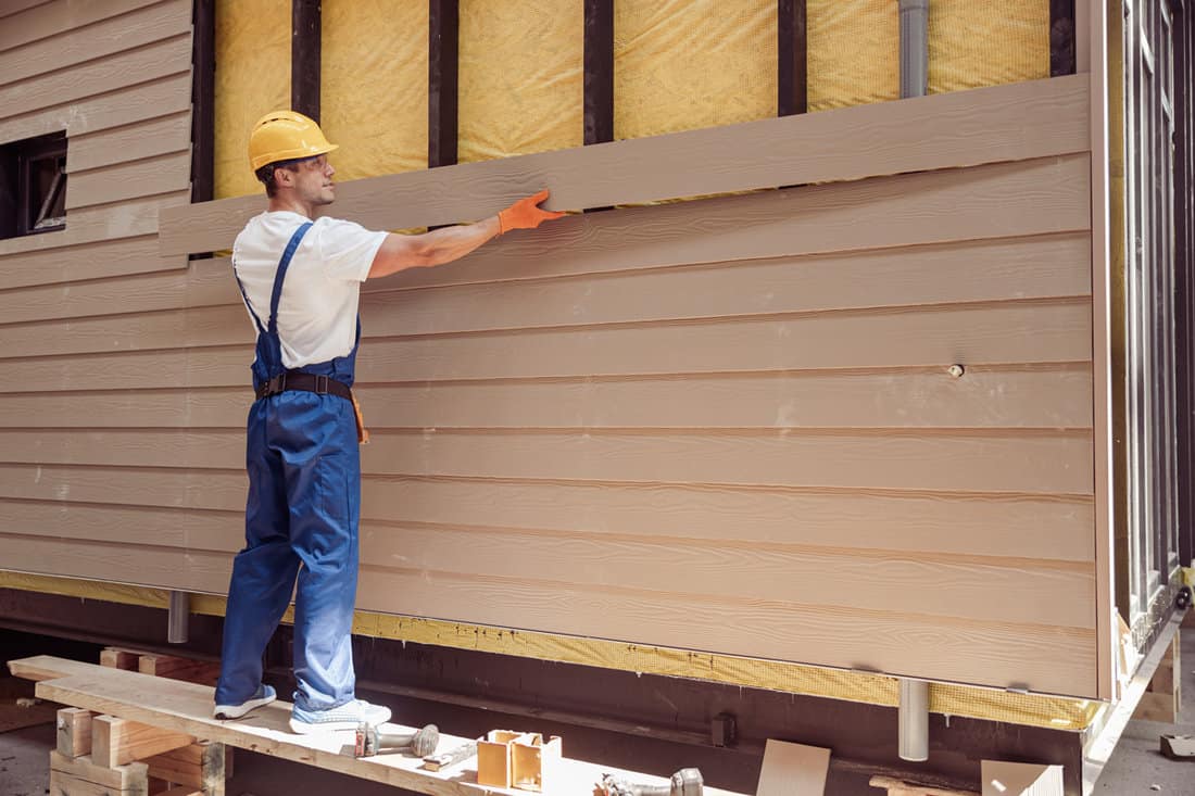 Worker installing wooden house siding