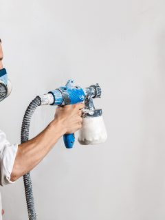 Worker painting wall with spray gun, Can You Spray Paint Over Powder Coat?