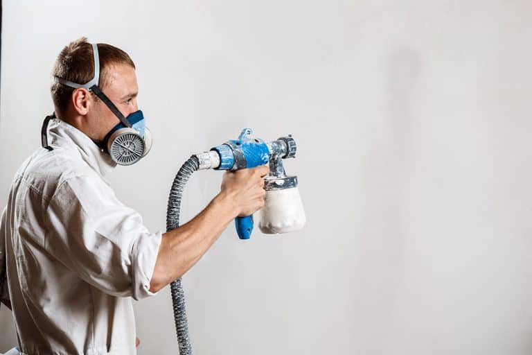 Worker painting wall with spray gun, Can You Spray Paint Over Powder Coat?