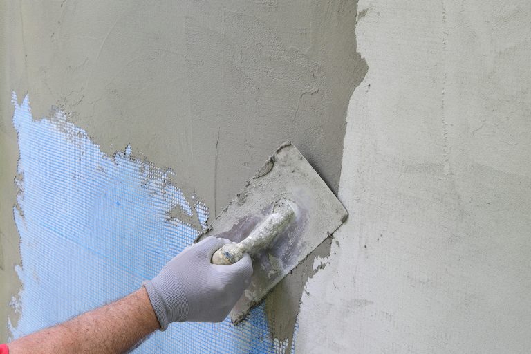 Worker spreading cement on wall, Can You Cement Over Drylok?