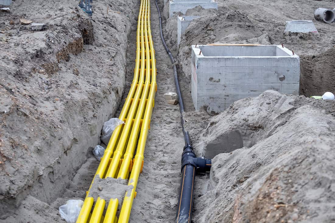 Yellow PVC pipeline for cable systems buried in the sand. Polyethylene pipes are used as channels for optical cables and providing protection for telecommunication and electrical power cables. 