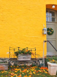 Yellow brick house entrance with seasonal wreath on door and porch window, What Color Siding Goes With Yellow Brick?