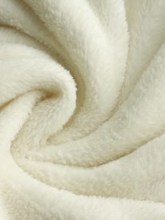 a warm, white, plush micro fleece blanket fabric is swirled into a circular pattern background, Are Fleece Sheets Warmer Than Flannel