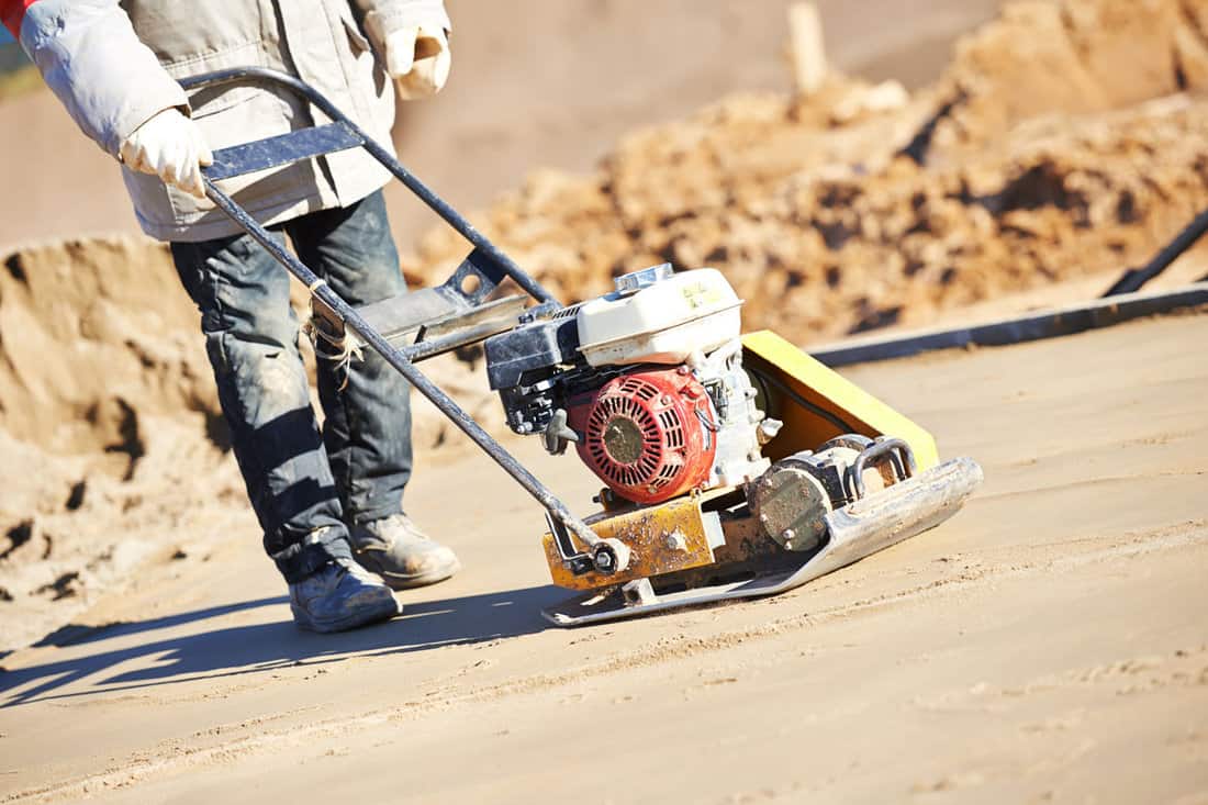 builder worker sand ground compaction vibration