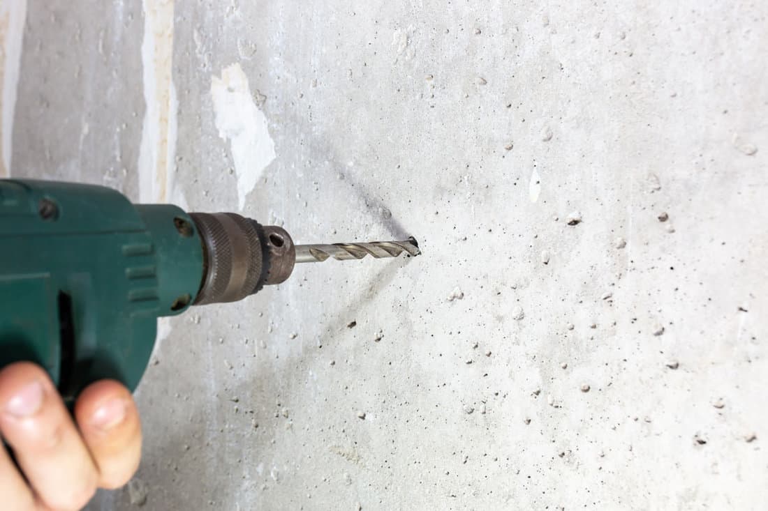 carpenter man drilling hole concrete wall repair fix
