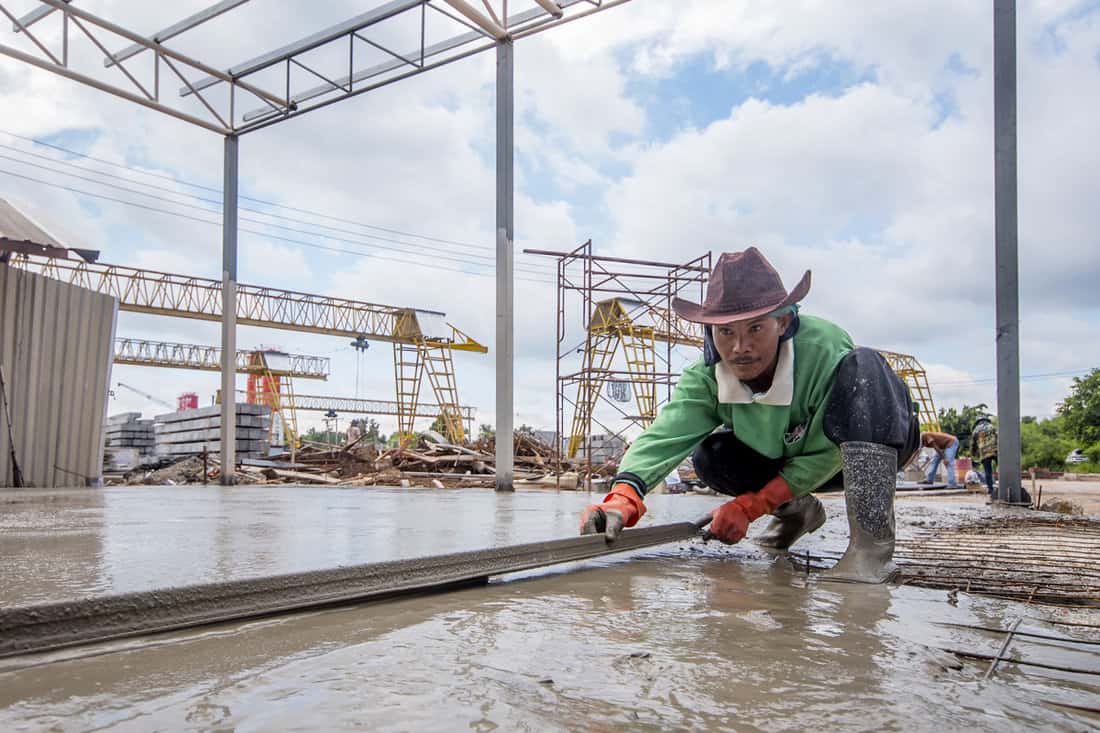 concrete workers plasterers levelling liquid cement at construct