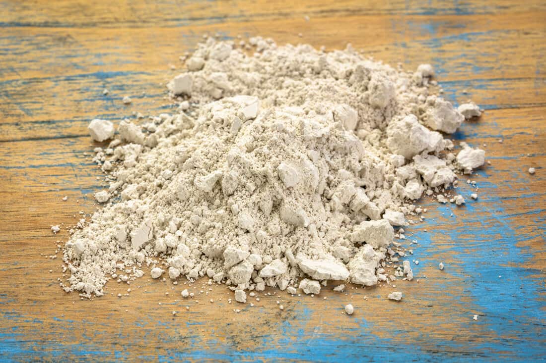 food grade diatomaceous earth supplement - small pile of powder on a grunge wood