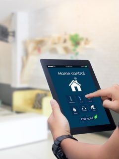 hands holding smart tablet with app smart home on blurred home living room, Openhab Vs Home Assistant Pros & Cons - Which Is Best For Your Home?