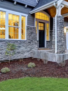 Front covered porch design boasts stone columns and rock siding that creates immense curb appeal of luxurious home. Northwest, USA - How To Install Novik Stone Siding [Step By Step Guide]
