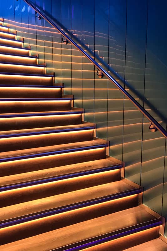 wonderful Blight light reflection from Wooden stairs against the wall attached stainless steel handrails