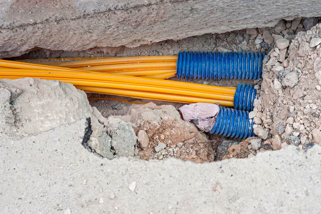 worker inserts fiber optic cables buried