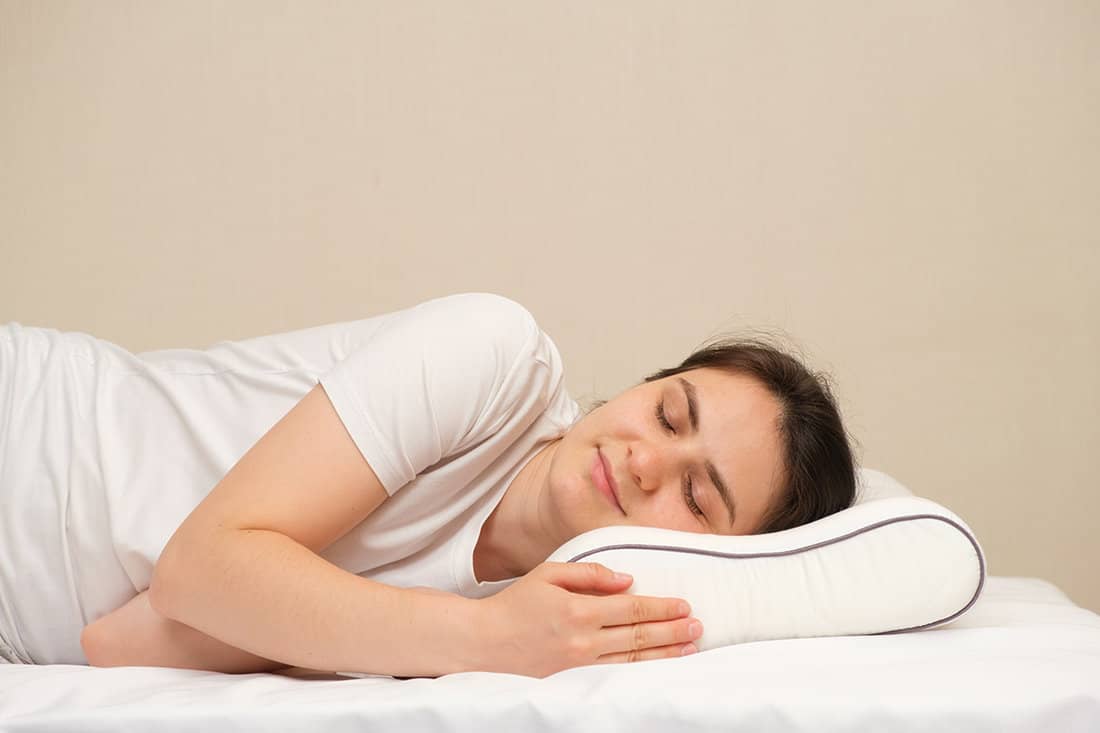 A woman sleeps on an orthopedic pillow made of memory foam