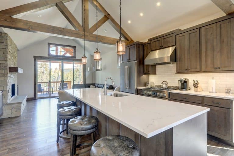 Amazing modern and rustic luxury kitchen with vaulted ceiling and wooden beams, long island with white quarts countertop and dark wood cabinets., Can You Paint Quartz Countertops?