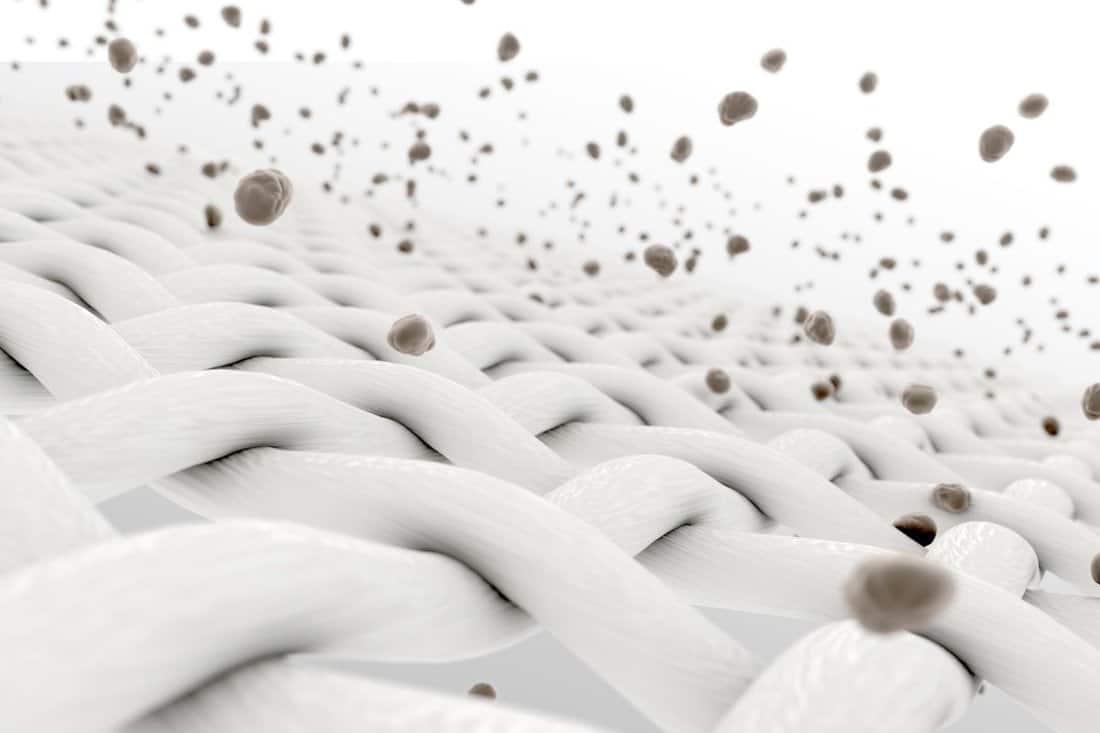 An extreme magnification of white individual fabric threads being penetrated by dirt particles on an isolated background 