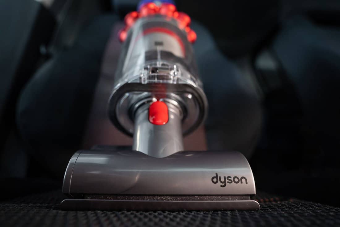 Close up of the Mini motorhead of Dyson Cyclone V10 Fluffy vacuum cleaner on car seats with car interior background. Ready for cleaning.