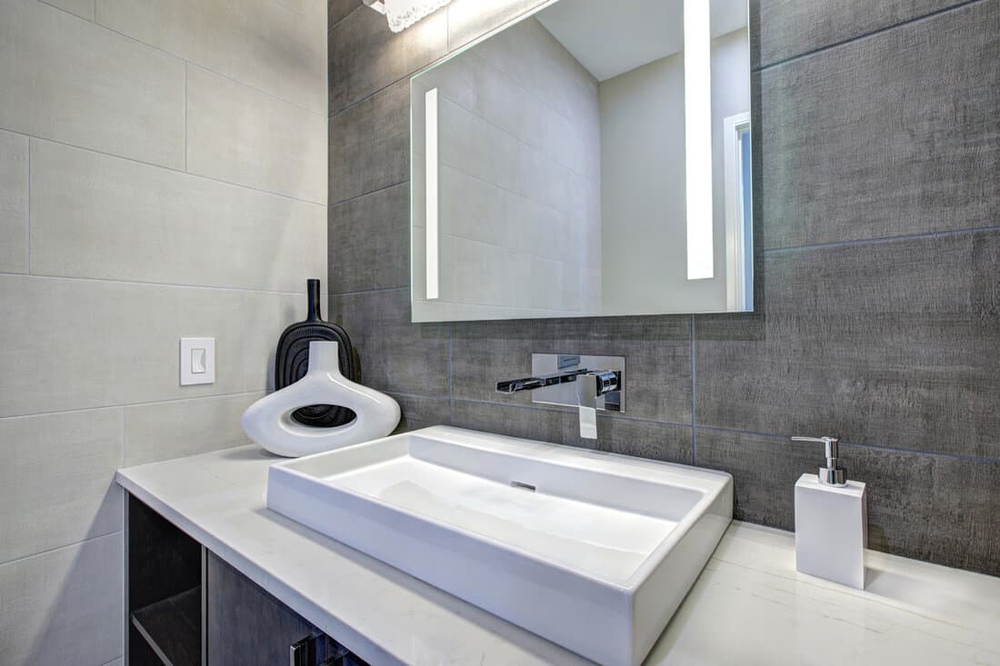 Contemporary bathroom interior with tile wall surround in grey tones.