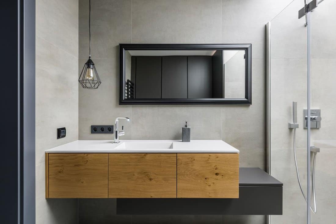 Gray bathroom with modern countertop basin, mirror and shower.