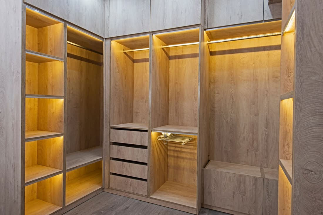 Interior design decor furnishing of luxury show home bedroom showing walk in wooden wardrobe closet furniture 