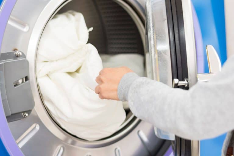 Laundry washing machine. A hand putting or getting some bed sheets from or into the laundry washing machine, How To Dry Fleece Sheets