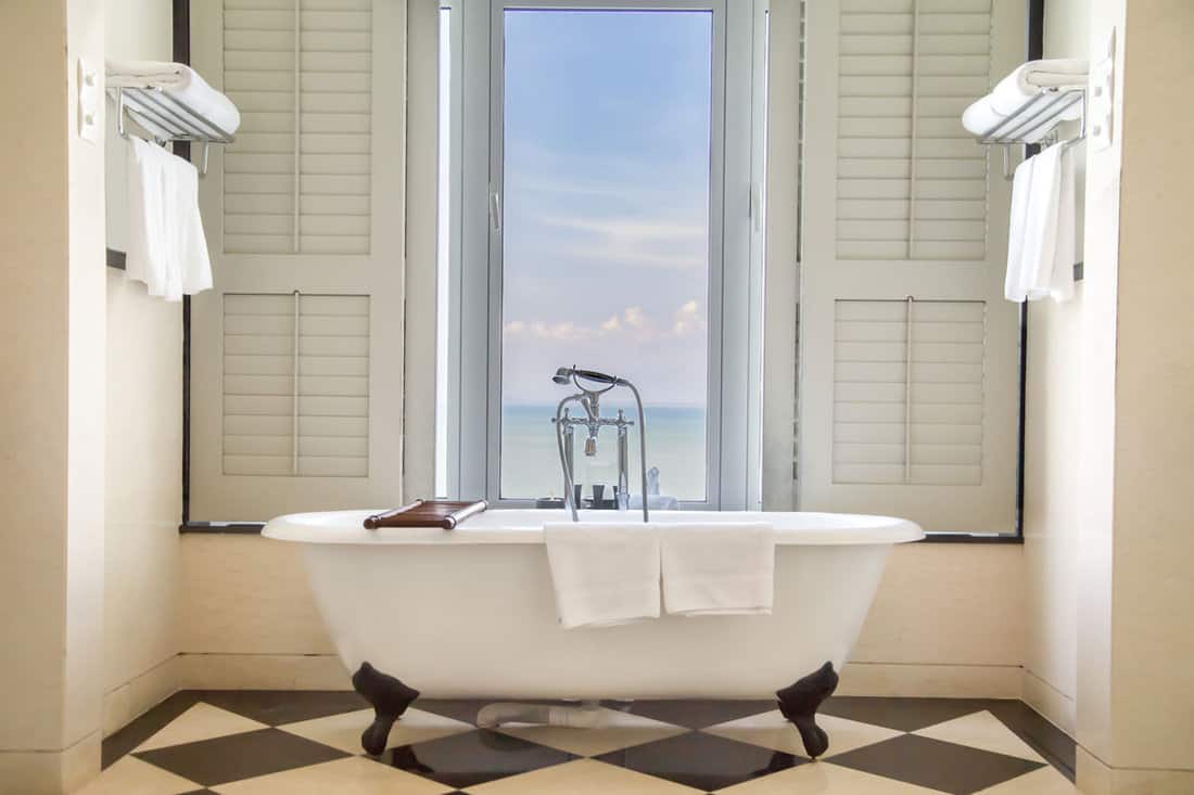 Luxury classic bathtub in bathroom with relaxing ambient and window with scenic sea
