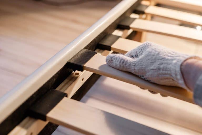 A hand in glove assembling bed, connecting slats to bed frame, Do You Need A Bed Frame With A Box Spring?