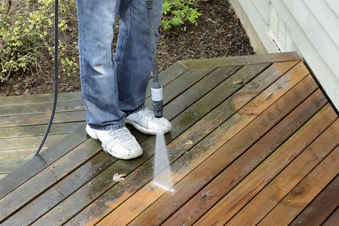 Man Using Power Washer to remove the molds in the wood